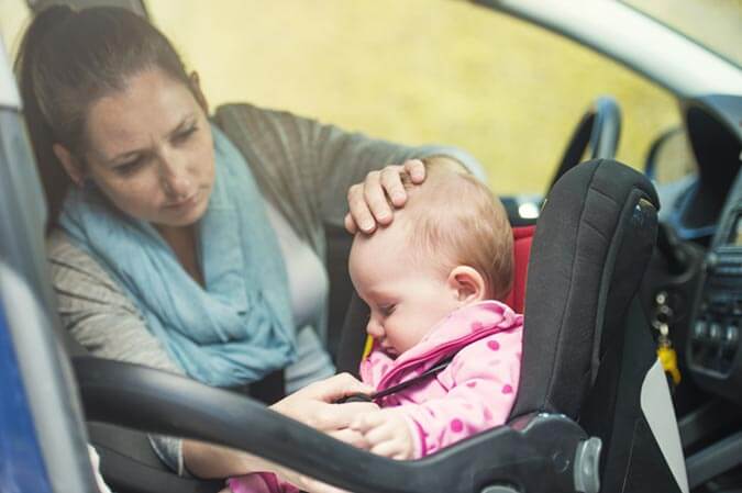 mother inaccurately strapping baby into front seat car seat