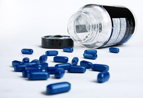 A transparent pill bottle with a black label lies on its side with its cap removed